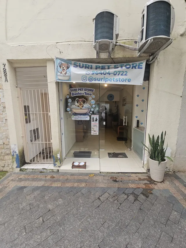 Fachada da Suri Pet Store: portão branco aberto e a loja ao fundo, na Rua Coriolano
